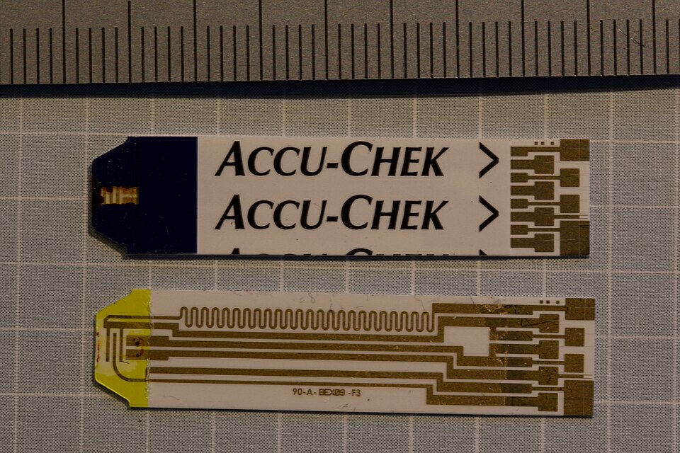 two used Accu-chek cash for test strips for their blood glucose test system for diabetics. The lower one has had the cover peeled off to show the circuit