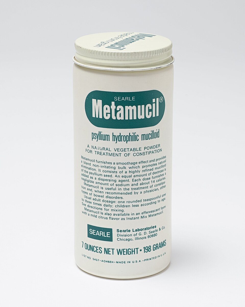White plastic container with white painted screw capped metal lid. The main label is "Metamucil." Extensive descriptive and use information is printed on the container in green. The container is full with original seal intact. Psyllium hydrophilic mucilloid is a bulk-forming oral laxative. This type