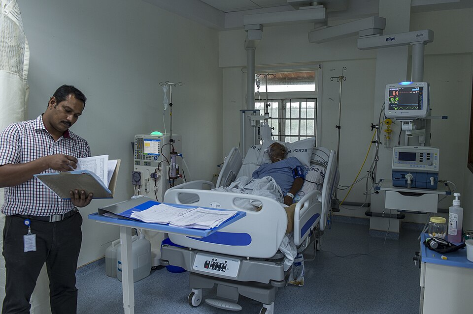 One of the hospital staff is reviewing the medical charts of a patient in the ICU.