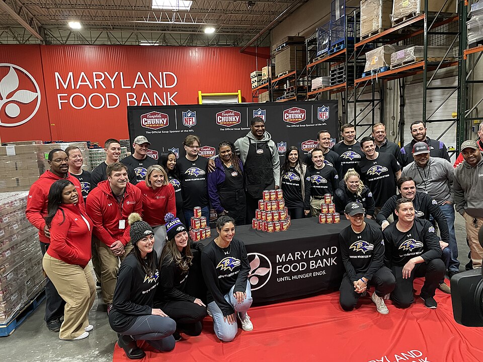 Calais Campbell (center left) poses with his mother, Nateal Campbell, along with Baltimore Ravens community relations staff and representatives from the Maryland Food Bank during his charitable partnership event with Campbell’s Soup.
