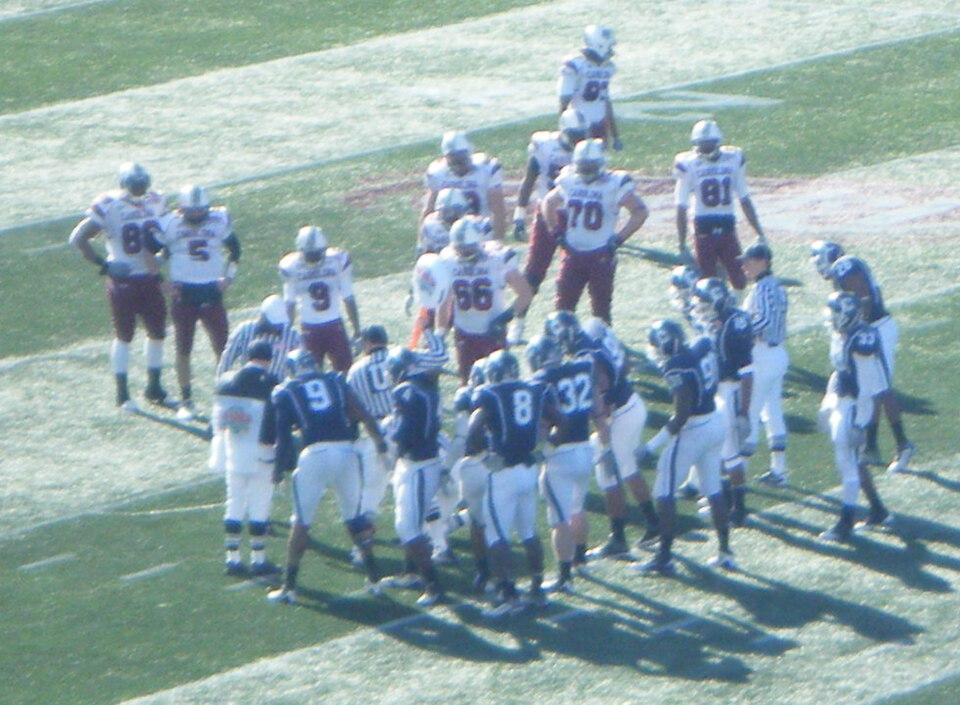 Connecticut and South Carolina football players look on as officials measure to see if en:Stephen Garcia's fourth down en:quarterback sneak attempt gave the Gamecocks enough yardage for a first down. The ball would be short of the yardage stick, giving possession of the ball to UConn.