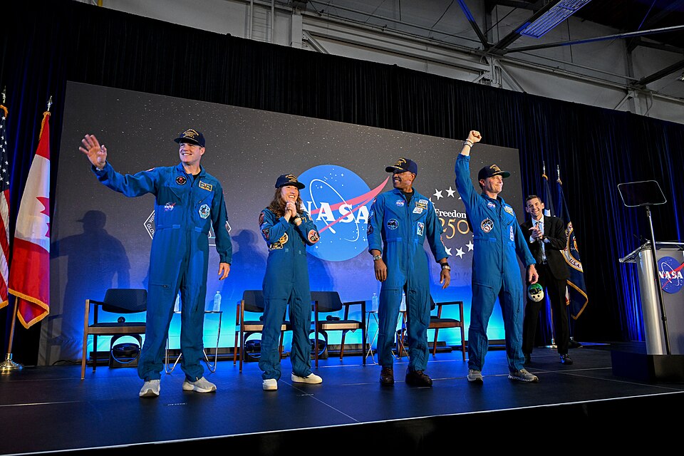 jsc2026e022288 (April 11, 2026) – The Artemis II crew and NASA Administrator Jared Isaacman, pictured here among the crowd of friends, family, and colleagues assembled for the return of the crew at Ellington Airport near NASA’s Johnson Space Center in Houston on Saturday, April 11, 2026. The Artemis