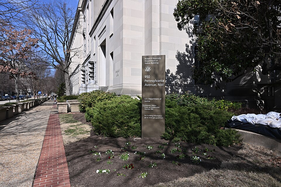 The corner of the Robert F. Kennedy Department of Justice Building, with the sign and address visible. 950 Pennsylvania Avenue NW, Washington, DC 20530.