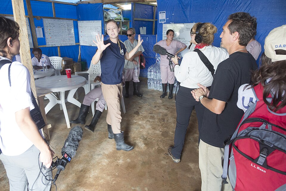 Maia Andrews, center, acting communications officer for International Medical Corps, gives a tour of an active Ebola treatment unit to members of the press, U.S. Agency for International Development personnel and members of the U.S. Department of State in Suakoko, Liberia, Nov. 22, 2014. United Assi
