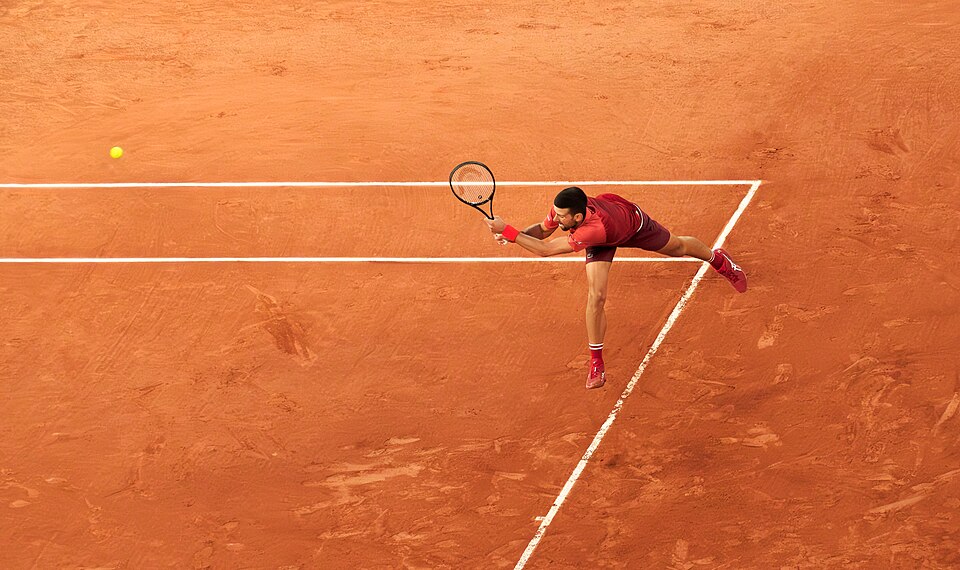 Novak Djokovic returning a serve with his backhand at the 2024 French Open (Roland-Garros), during his first round match against Pierre-Hugues Herbert (win 6/4, 7/6, 6/4) on court Philippe-Chatrier.