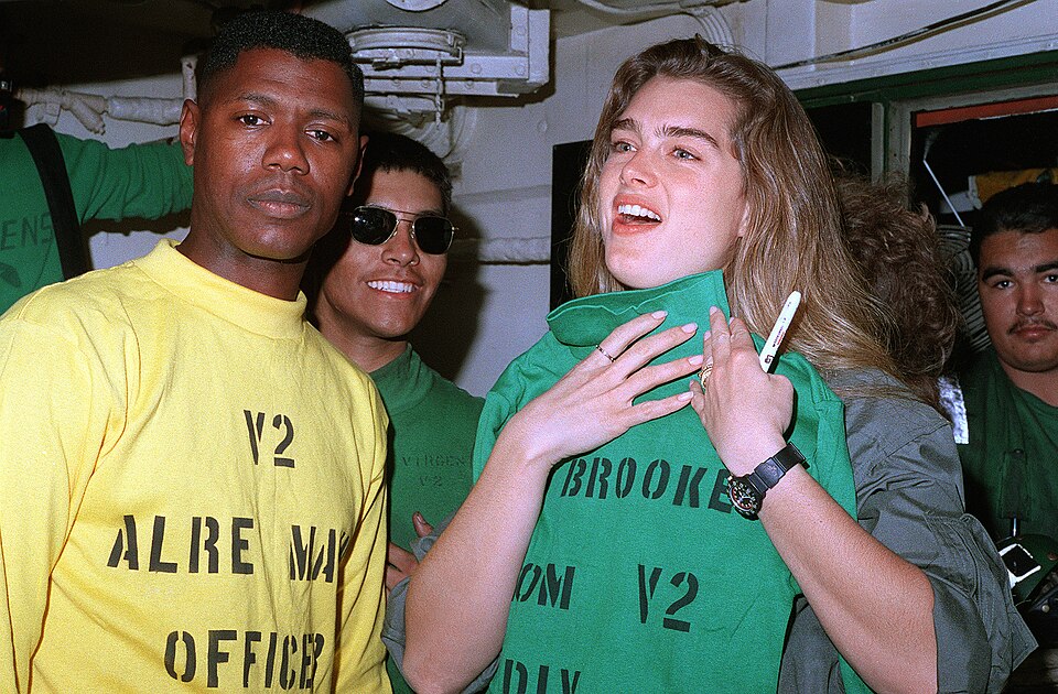 Actress Brooke Shields holds up a flight deck jersey presented to her by U.S. Navy Ensign Richard Jones, the aircraft launching and recovery equipment (ALRE) maintenance officer aboard the aircraft carrier USS Midway (CV-41). Shields' visit to the Midway was part of a tour sponsored by the United Se