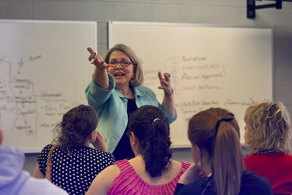 A college professor teaching in a university classroom full of students