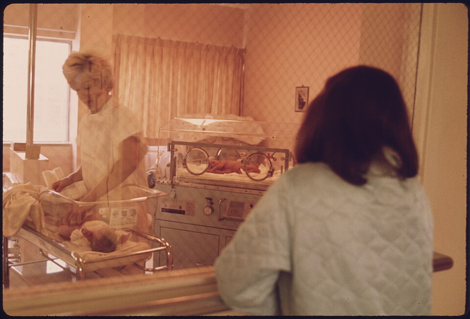 A NEW MOTHER VIEWS HER CHILD IN THE NURSERY OF LORETTO HOSPITAL IN NEW ULM, MINNESOTA. THERE ARE TWO HOSPITALS IN THE... - NARA - 558170