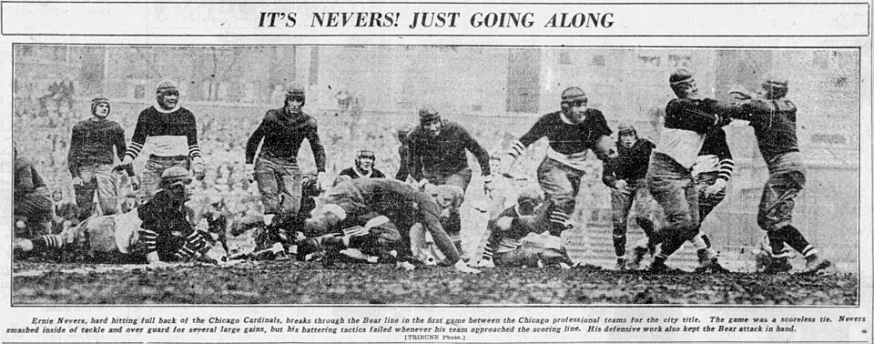 Caption text says "Ernie Nevers, hard hitting full back of the Chicago Cardinals, breaks through the Bear line in the first game between the Chicago professional teams for the city title. The game was a scoreless tie. Nevers smashed inside of tackle and over guard for seyeral large gains, but his ba