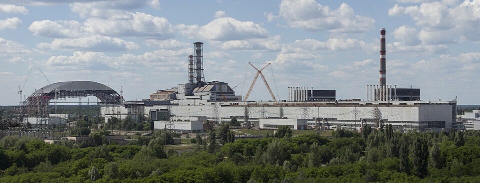 A stitched panorama view of the Chornobyl Nuclear Power Plant site in Ukraine, pictures taken in June 2013. Descriptions of the buildings from left to right: First half of the New Safe Confinement - after second lifting operation (has not yet reached its final height), reactor 4 with existing shelte