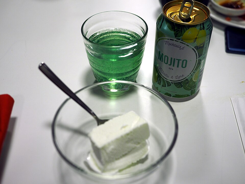 A can of alcohol-free mojito with its contents poured into a glass along with a bowl of vanilla ice cream.