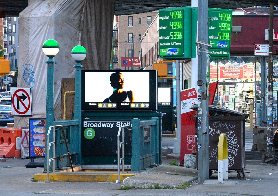 Entrance to the G train at Broadway Station next to a gas pump.