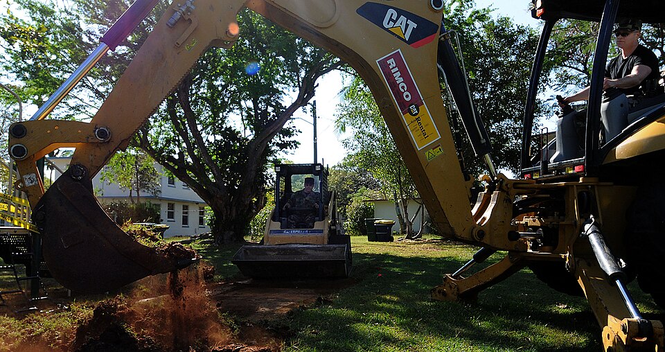 COAST GUARD AIR STATION BORINQUEN, Puerto Rico -- Tech. Sgt. David Bailey (right), a heavy equipment operator with the Alaska Air National Guard's 176th Civil Engineer Squadron, scrapes sod from a children's playground while Master Sgt. Scott Peterson, superintendant of the squadron's Heavy Equipmen