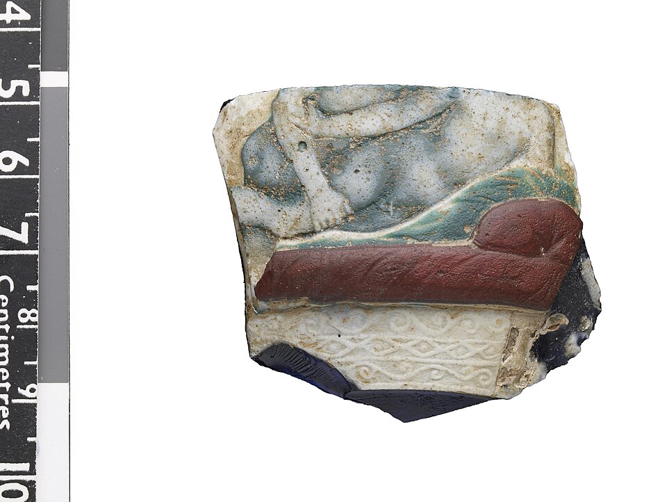 Fragment of an open vessel in translucent dark blue, opaque light green, opaque white and opaque brownish red cameo glass. The decoration shows a homosexual scene. (BM 1956,0305.1)
.