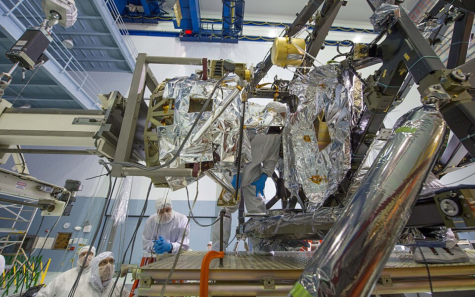 Engineers are checking to make sure that MIRI is precisely positioned with the ISIM as it slides into position. They have to make sure it's installed exactly where it needs to be within the width of a thin human hair. Visible is MIRI's pickoff mirror, which is the protrusion on the right side of the
