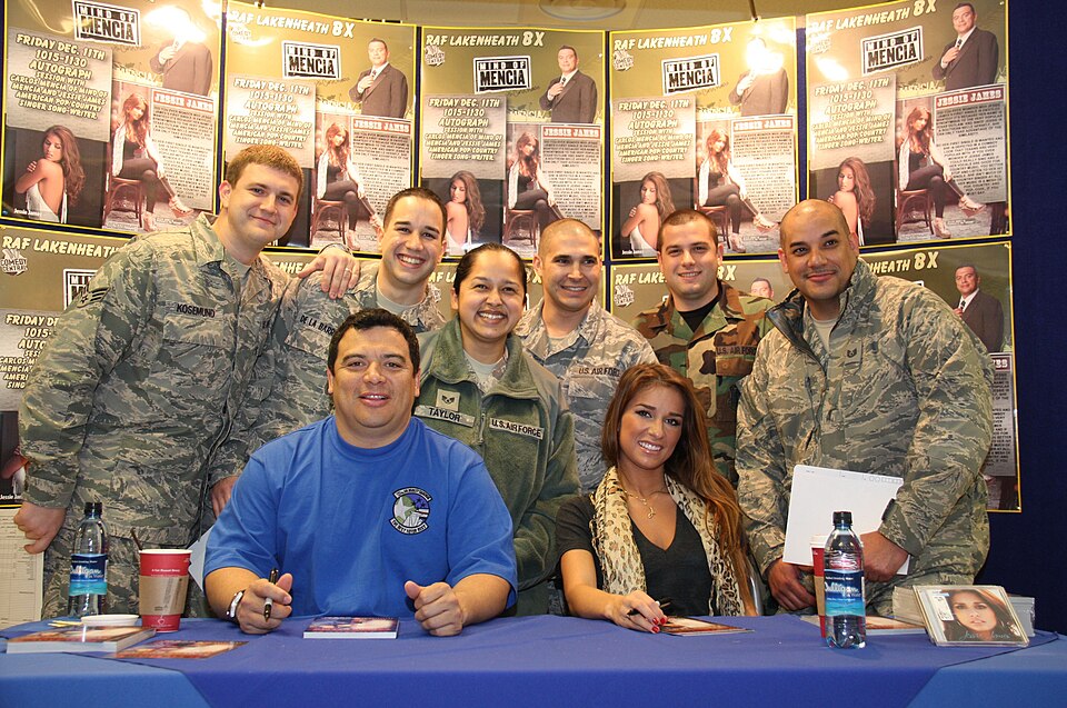 Carlos Mencia and Jessie James taking a break from signing autographs at the RAF Lakenheath Base Exchange for a group photo with Liberty Warriors on December 11, 2009