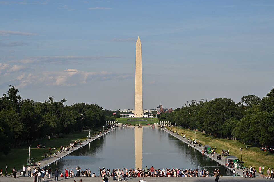 The Washington Monument reflecting in the Lincoln Memorial Reflecting Pool after the pool was restored and painted blue.  There is currently an algae bloom being cleaned up and equipment related to that cleanup is visible on the right side of the pool. At this point the algae has been cleared from t