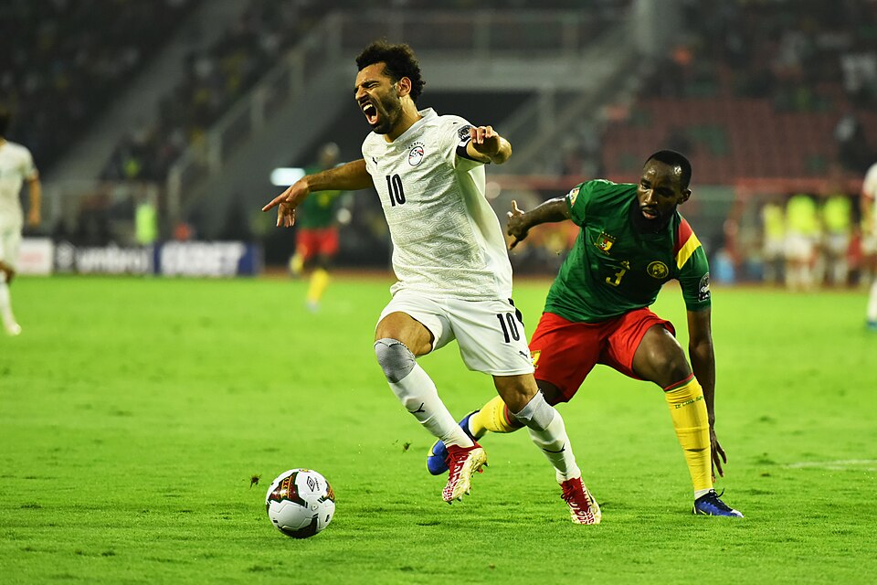 Cette photo montre un duel entre Mohamed Salah et un joueur camerounais lors d'un match de la demi finale au stade de Olembé Yaoundé