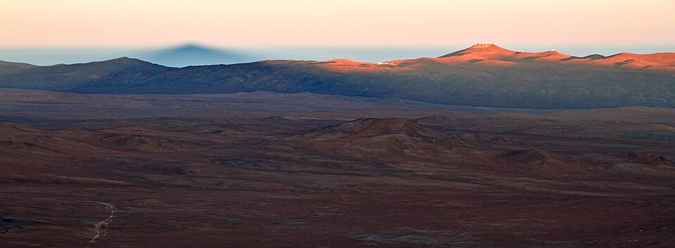 The Atacama Desert, and Sierra Vicuña Mackenna (mountain range) of the the Cordillera de la Costa System (Chilean Coast Ranges), Chile.
In this photograph, taken by ESO Photo Ambassador Gianluca Lombardi, the Sun is rising and bathing the Chilean Atacama Desert in a familiar soft reddish glow. But t