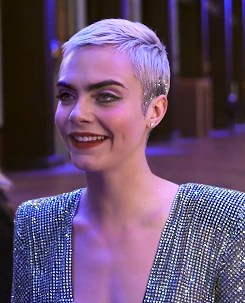 Cara Delevingne smiling in Paris with dyed cropped hair and a sequined garment while at the Red carpet of Luc Besson's Valerian and the City of a Thousand Planets.