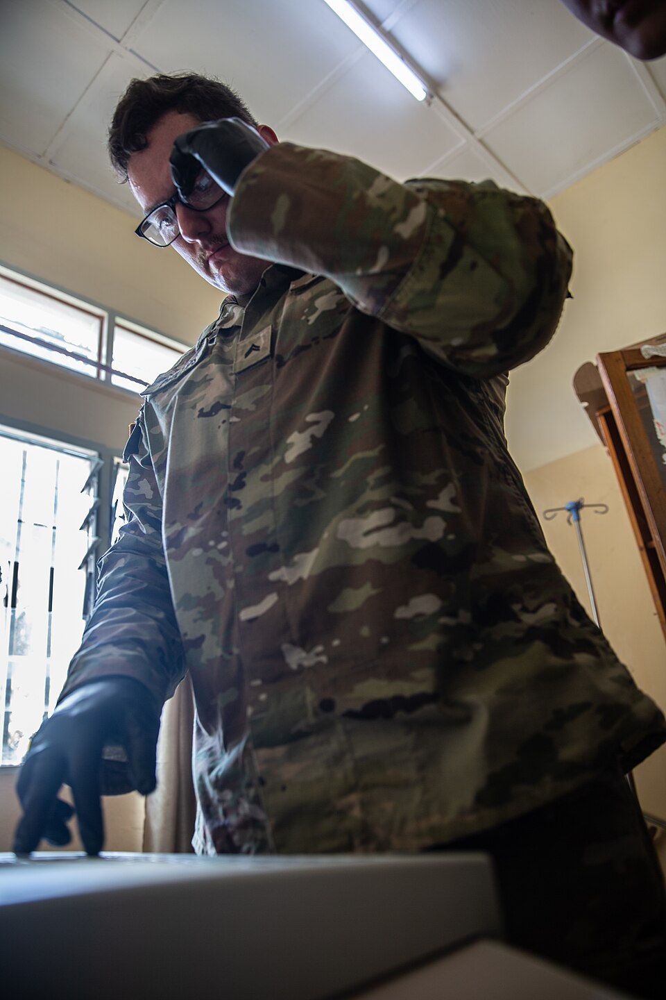 U.S. Army Cpl. Jake Phillips, a biomedical equipment specialist (68A), assigned to the 16th Hospital Center, 44th Medical Brigade, runs diagnostic tests on a broken electrocardiogram (EKG) printer at Kamenge Military Hospital. The machine processes vital readings on patients and improves the hospita