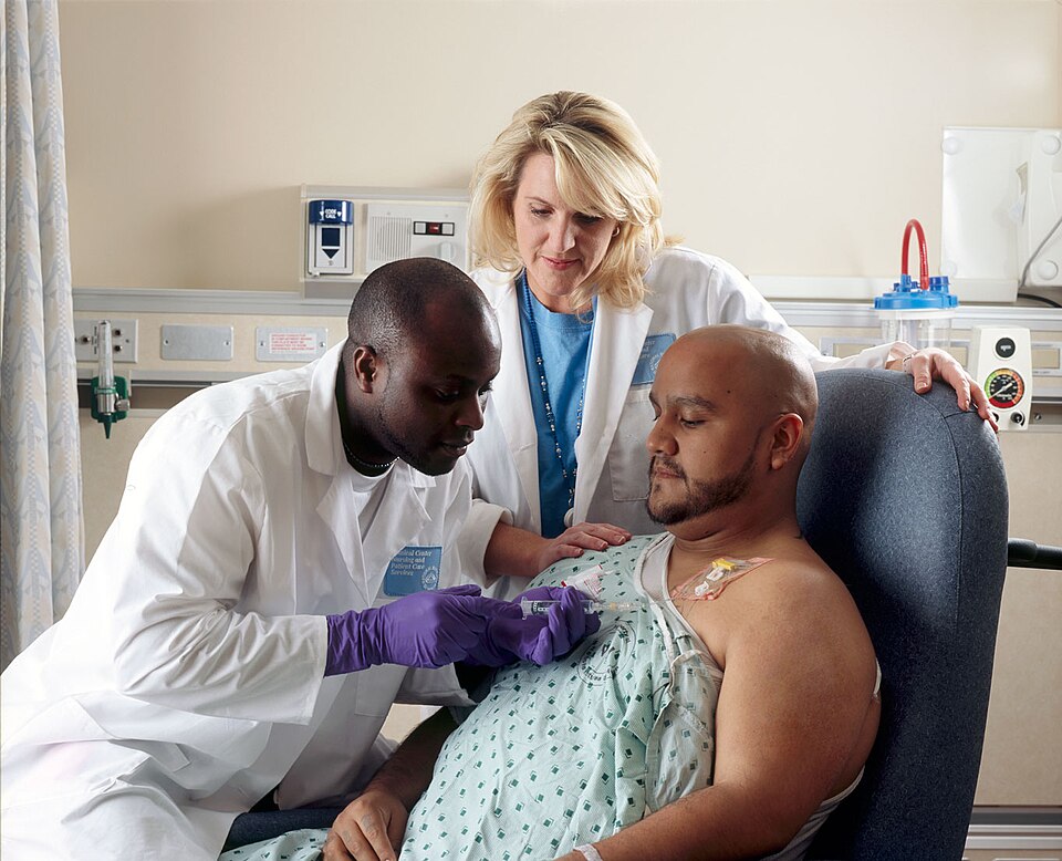 Title Patient Receives ChemotherapyDescription A Hispanic male patient receives Chemotherapy from a African-American Nurse through a port that is placed in his chest area. A caucasian female nurse looks on.Topics/Categories  Locations -- Clinic/Hospital People -- Adult People -- Health Professiona