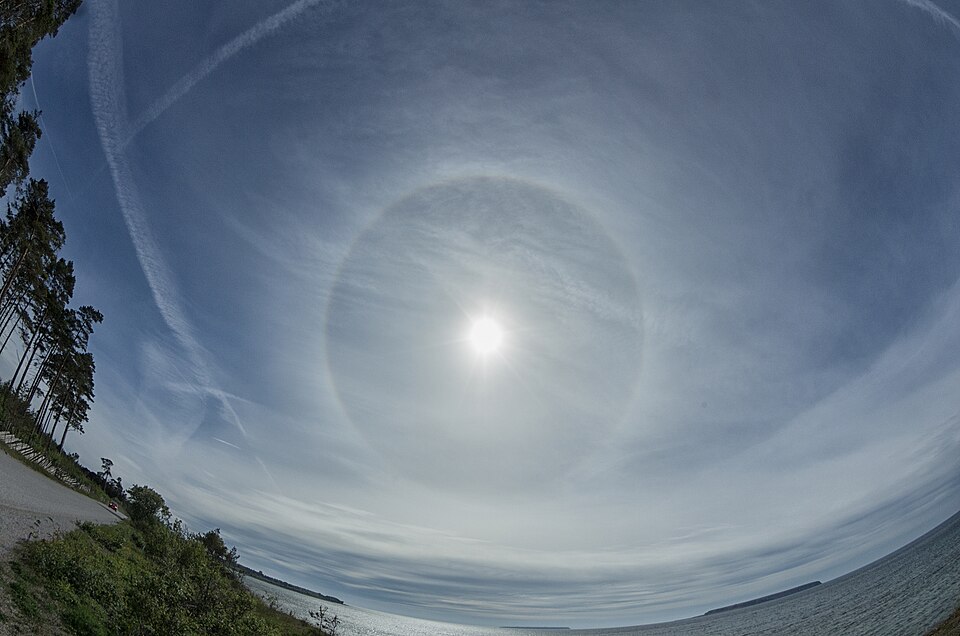 Natural reserve Ekstakusten, Gotland, Sweden that stretches along the shore. Islands straight ahead: natural reserves Stora Karlsö and Lilla Karlsö. In the sky a 22 degree halo.  
Fisheye lens that kept the halo round and made the horizon rounded.