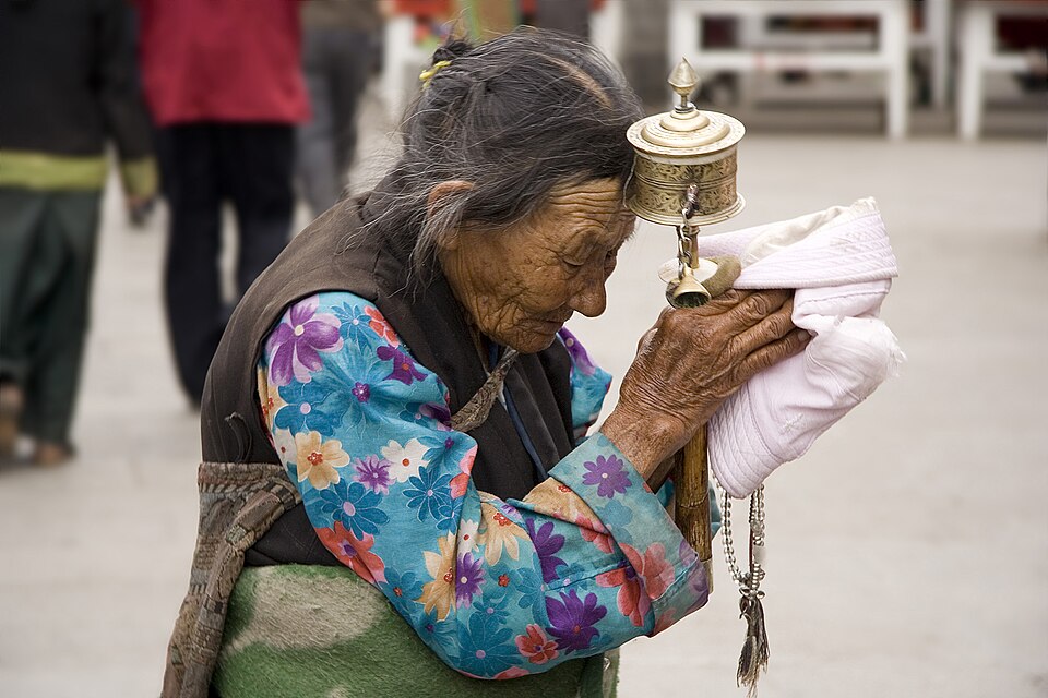 Tibet: An elderly Tibetan women holding a prayer wheel on the Lhasa's pilgrimage circuit of Barkhor. The Barkhor, a quadrangle of streets that surrounds the Jokhang Temple, is both the spiritual heart of the holy city and the main commercial district for Tibetans.