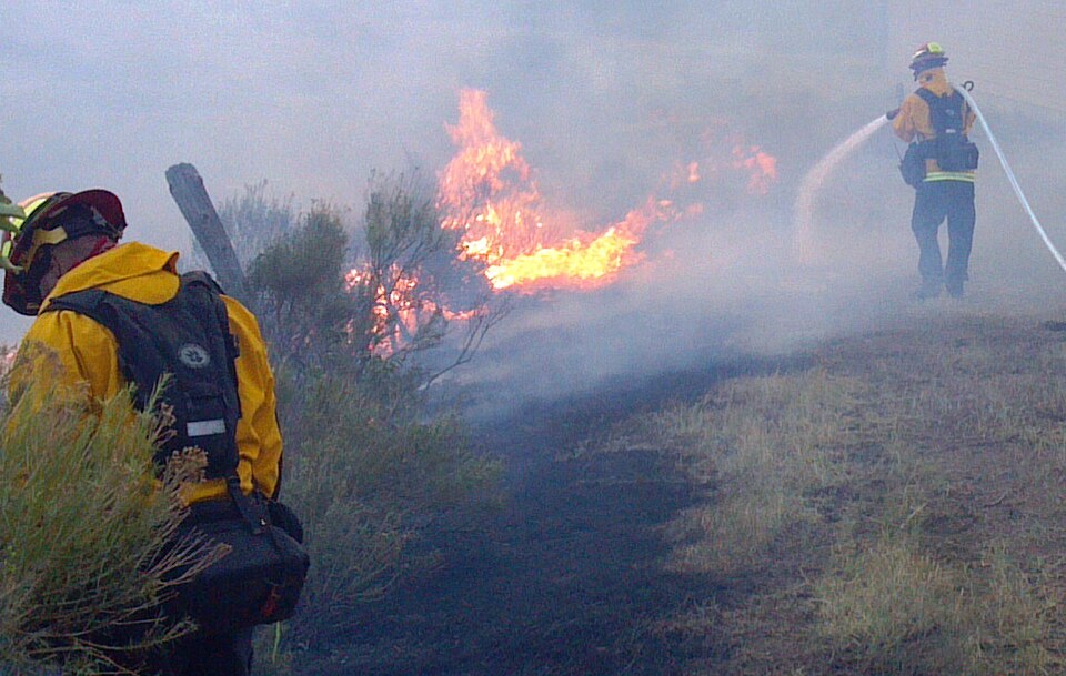 Firefighter wets down area in front of private home in effort to retard the advance of the High Park Wildfire on Thursday, June 10, 2012. The High Park Wildfire located approximately 15 miles west of Fort Collins, CO has consumed over 65,738 acres of forest and grassland with approximately 189 homes