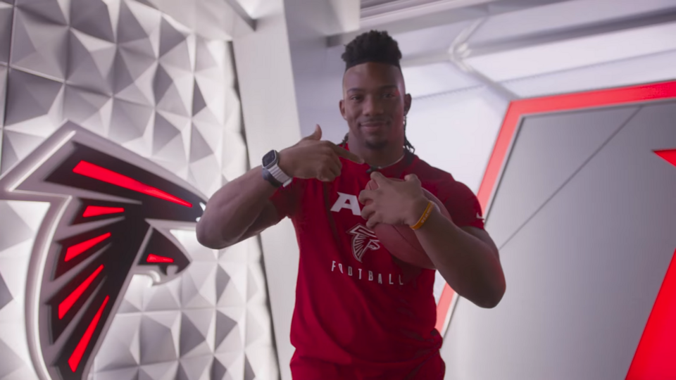 Running back, Bijan Robinson, films a promotional video following him being drafted by the Atlanta Falcons in the first round of the 2023 NFL Draft. Image is a screen shot of Youtube video ~ 01:04.