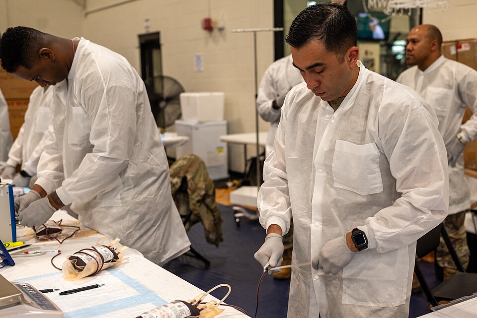 Army Reserve Staff Sgt. Juan Gomez, a medical laboratory specialist with the San Antonio, Texas-based 7389th Blood Detachment, clears a blood collection bag tube line to begin processing the donation at the Armed Services Blood Program blood drive during Cadet Summer Training at Fort Knox, Ky., July