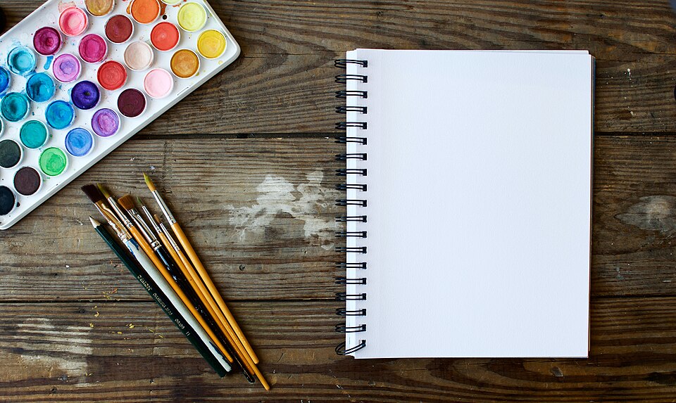 A notebook with paint brushes and color palette.
