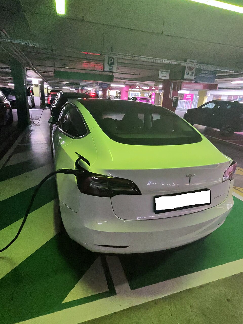 Una Tesla Model 3, in fase di ricarica mediante un caricatore installato presso il Tesla Destination Charging, situato all'interno di un centro commerciale, è stata fotografata. Il veicolo è parcheggiato in modo da coprire parzialmente la passerella e parzialmente il parcheggio destinato. La vettura