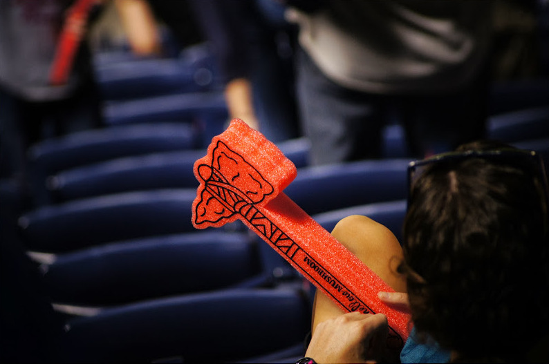 A man at an Atlanta Braves game holds a Braves tomahawk.