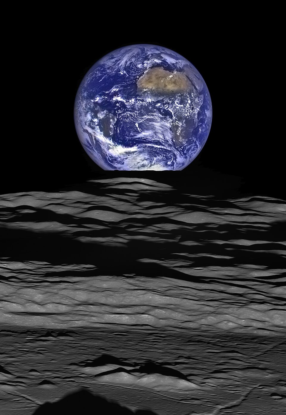 The Earth straddling the limb of the Moon, as seen from Lunar Reconnaissance Orbiter above Compton crater. The shadow in the foreground is from the crater's central peaks, while the mountains just above it can be seen in the 10 o'clock position within the crater in this image or the 12 o'clock posit