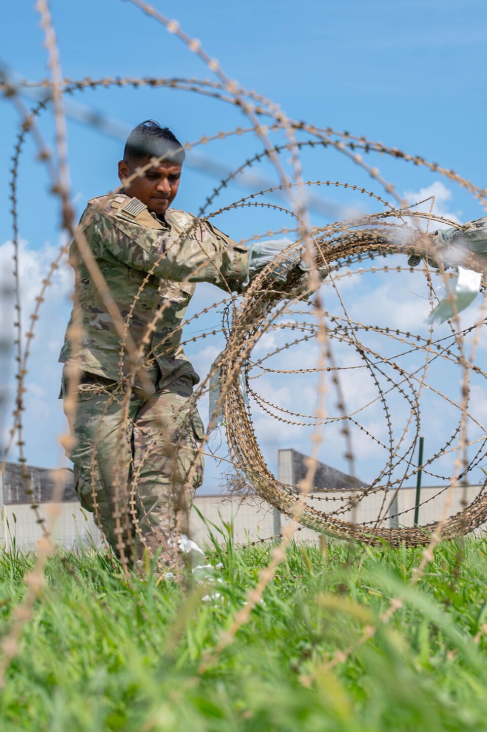 Sgt. Desal Patel, an intelligence analyst assigned to Headquarters and Headquarters Company, 501st Military Intelligence Brigade, collapses concertina wire around a simulated Tactical Operation Center during Ulchi Freedom Shield on Camp Humphrey, Republic of Korea, Aug 20, 2025. The task was part of