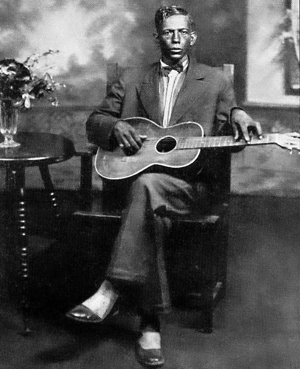 The only extant photograph of American bluesman Charley Patton, circa 1929. Patton sits at a chair with a Stella guitar. The portrait was likely taken in Grafton, Wisconsin—the headquarters of Paramount Records—at either a photography studio or recording studio. An image of Patton's face (cropped fr