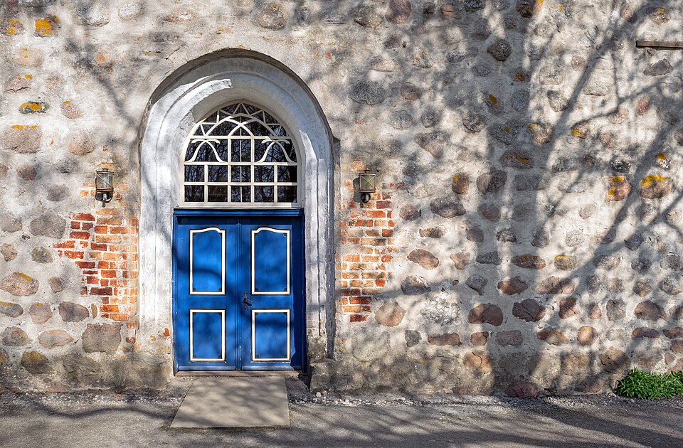 View of the main portal of the Lutheran village church in Sanitz in the district of Rostock. The shadow in the image is cast by a nearby birch tree.