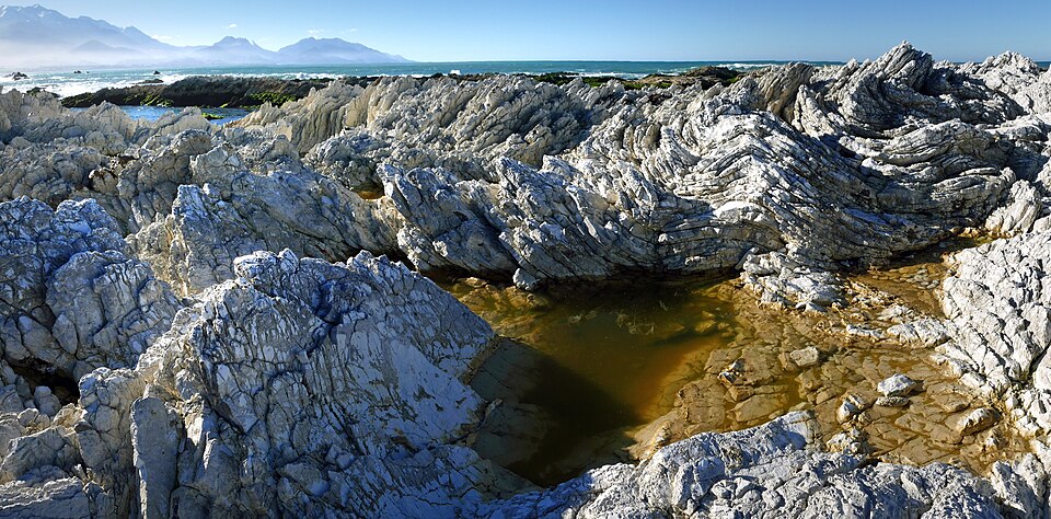 Oligocene tilted folded vertical limestone rocks on coast of Kaikoura South Island New Zealand 

Kaikoura is a coastal town on the South Island of New Zealand. It’s known for its abundant wildlife and its sperm whale population. The Kaikoura Peninsula Walkway winds from the town centre to lookout po