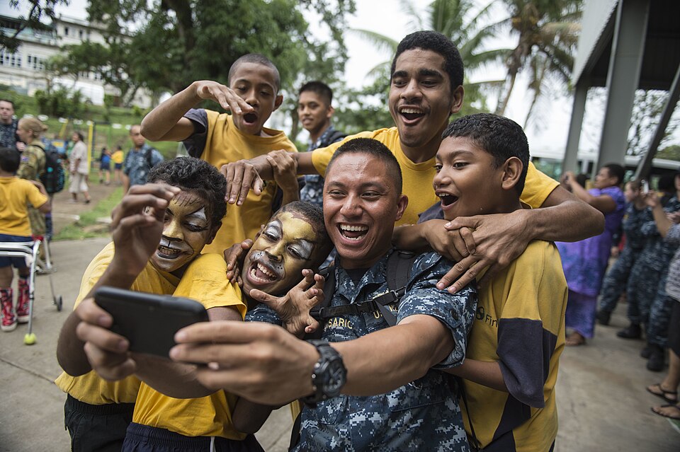 SUVA, Fiji (June 10, 2015) Lt. j.g. Jomer Belisario, a disbursing officer from Sacramento, Calif., takes a selfie with Fijian students at Hilton Special School during Pacific Partnership 2015. Fiji is Mercy’s first mission port of PP15. Pacific Partnership is in its tenth iteration and is the larges